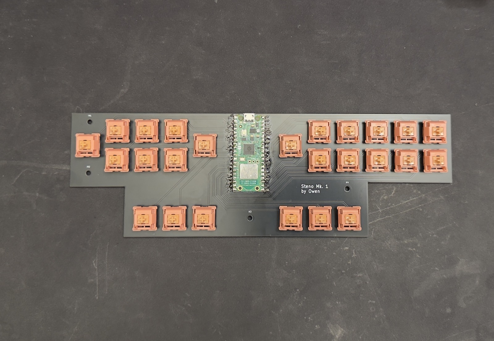 Bare 2-layer PCB with 25 switches seated and a Raspberry Pi Pico 2 W hand-soldered at centre; silkscreen reads Steno Mk. 1 by Owen